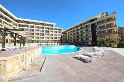 a hotel with a swimming pool and lounge chairs at Menada Luxor Apartments in Sveti Vlas