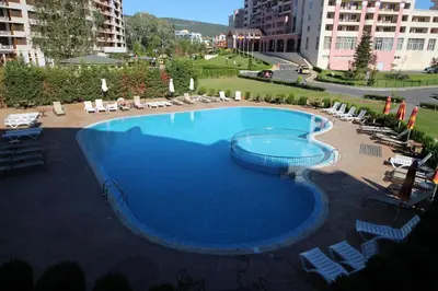 a large blue swimming pool with chairs and umbrellas at Menada Sunny Beach Plaza Apartments in Sunny Beach