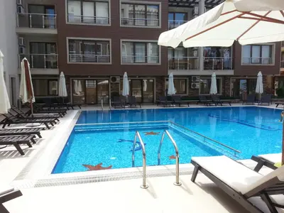 a pool with chairs and umbrellas in a hotel at Menada Horyzont Apartments in Sozopol