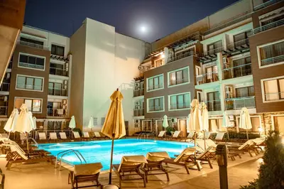 a pool with chairs and umbrellas next to a building at Menada Horyzont Apartments in Sozopol