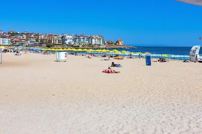a group of people on a beach with umbrellas at Menada Horyzont Apartments in Sozopol