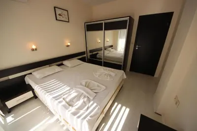 a large white bed in a room with a mirror at Menada Horyzont Apartments in Sozopol