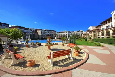a person sitting on a bench in a courtyard at Menada Kavaci Sozopol Apartments in Sozopol