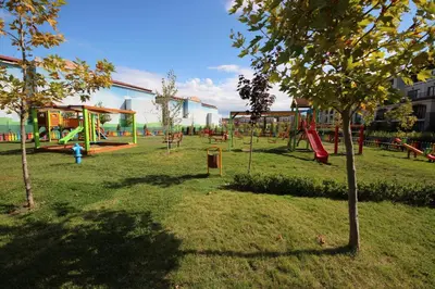a park with a playground with swings and a tree at Menada Kavaci Sozopol Apartments in Sozopol