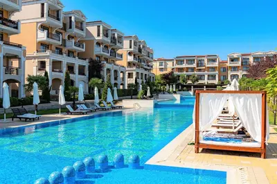 a swimming pool with a bed and some buildings at Menada Kavaci Sozopol Apartments in Sozopol