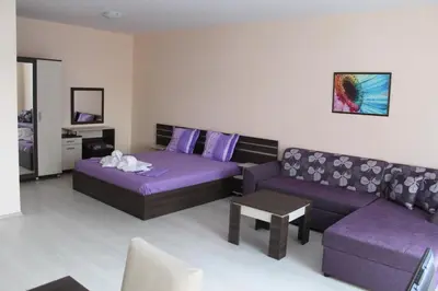 a living room with a purple couch and a couch and a table at Rose Garden Omax Apartments in Sunny Beach