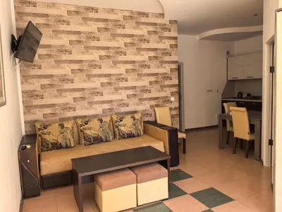 a living room with a couch and a brick wall at Rose Garden Omax Apartments in Sunny Beach