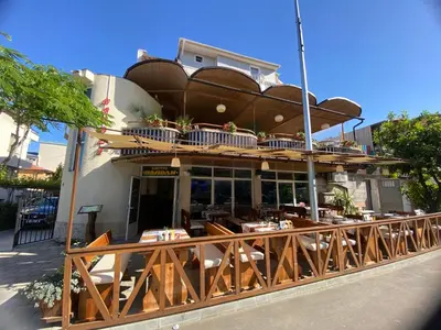 a restaurant with tables and chairs in front of a building at Guest house Napoli in Ravda