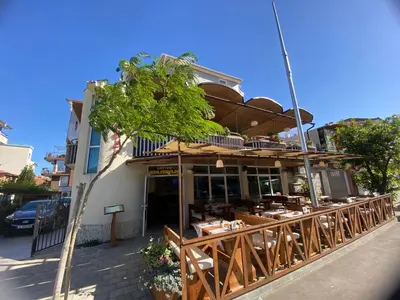 a restaurant with tables and chairs in front of a building at Guest house Napoli in Ravda