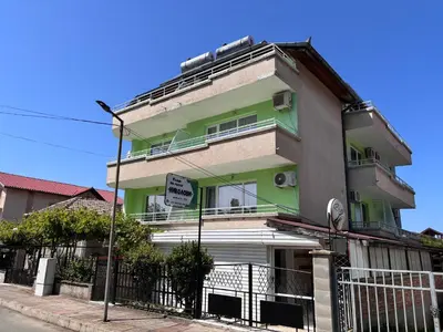 a green and white building with a sign in front of it at Guest House Nikolovi in Lozenets