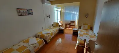 a room with four beds and a table and chairs at Guest House Nikolovi in Lozenets