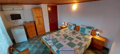 a small bedroom with a bed and a refrigerator at Guest House Nikolovi in Lozenets