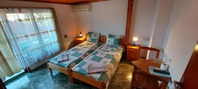 a bedroom with a bed and a table and a window at Guest House Nikolovi in Lozenets