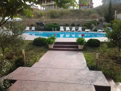 a pathway leading to a swimming pool with chairs at Villa Rouge in Sozopol