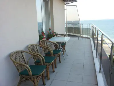 a balcony with chairs and a table and the ocean at Villa Rouge in Sozopol