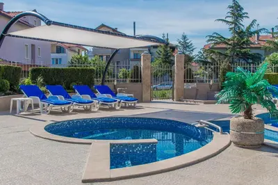 a swimming pool with blue chairs and a umbrella at Семеен хотел Адена in Chernomorets