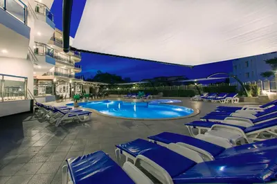 a swimming pool with blue and white lounge chairs at Семеен хотел Адена in Chernomorets