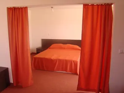 a bedroom with an orange bed and curtains at Hotel Bellisimo in Lozenets