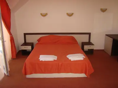 a bedroom with a orange bed with two nightstands and two towels at Hotel Bellisimo in Lozenets