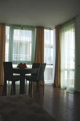 a dining room with a table and chairs and windows at Guest House ASK in Primorsko