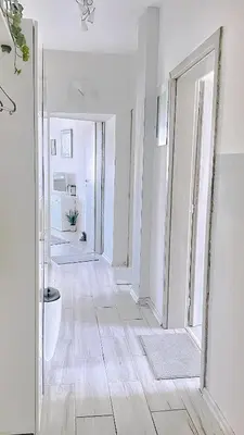 a hallway with white walls and wooden floors and a mirror at Venum in Varna City