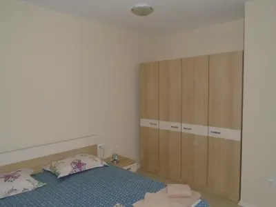 a bedroom with a bed and wooden cabinets at Nedev's Apartments in Kavatsi Area in Sozopol