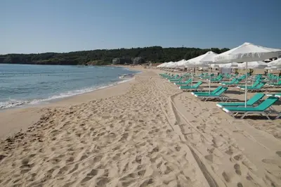 a beach with chairs and umbrellas and the ocean at Nedev's Apartments in Kavatsi Area in Sozopol