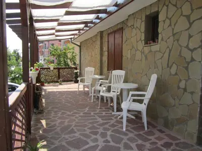 a patio with white chairs and tables on a stone wall at House Sofia in Sveti Vlas