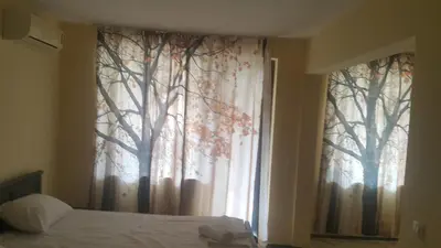 a bedroom with a window with trees on the curtain at Complex Strandzhata in Burgas City