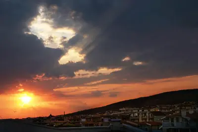 a sunset with the sun setting behind a city at JBH Hotel in Sveti Vlas