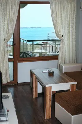 a living room with a table and a view of the ocean at JBH Hotel in Sveti Vlas
