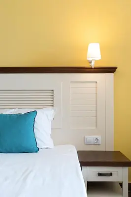 a bedroom with a bed with a blue pillow and a table at Hotel Evridika in Nesebar