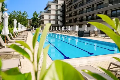 a swimming pool with chairs and umbrellas next to a building at Hotel Laguna Park Sunrise in Sunny Beach