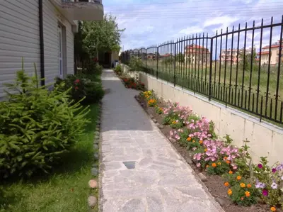 a sidewalk next to a fence with flowers at Morska Zvezda Guest House in Chernomorets