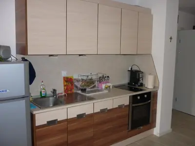 a kitchen with wooden cabinets and a sink at Ganozliev's Apartments in Kavatsi Area in Sozopol