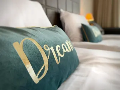a green pillow with the word tememia on it on a bed at Royal Beach Premium in Sunny Beach