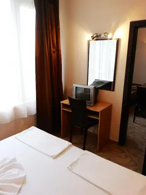 a hotel room with two beds and a desk with a mirror at Hotel Varly Bryag in Burgas City