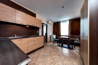 a kitchen with wooden cabinets and a sink and a table at Hotel Varly Bryag in Burgas City