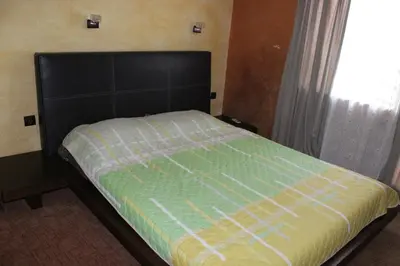 a bed with a black headboard and a window at Guest House Dara in Tsarevo