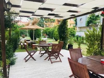an outdoor patio with tables and chairs and an umbrella at Hotel Elmaz in Lozenets