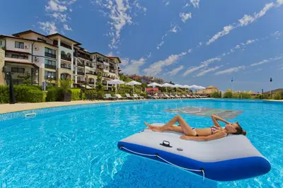 a woman laying on a raft in a swimming pool at Hotel Palace Marina Dinevi in Sveti Vlas