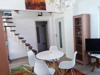 a room with a table and chairs and a spiral staircase at Studio Lilou in Varna City