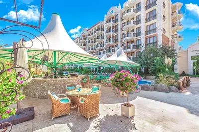 a patio with a table and chairs and a building at Harmony Suites Grand Resort in Sunny Beach