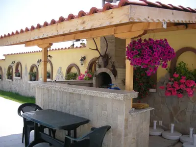 a stone outdoor kitchen with a table and flowers at Gardenia Suites in Sozopol
