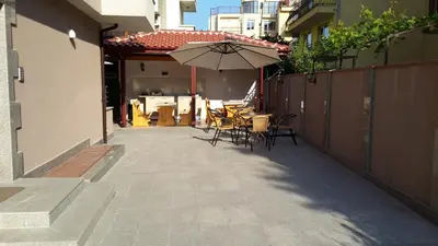a patio with an umbrella and tables and chairs at Guest House Donchevi in Primorsko