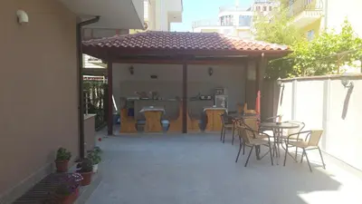 a patio with a table and chairs and a bar at Guest House Donchevi in Primorsko