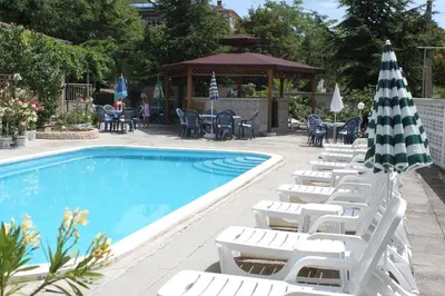 a group of chairs and an umbrella next to a swimming pool at Family Hotel Chris in Sveti Vlas