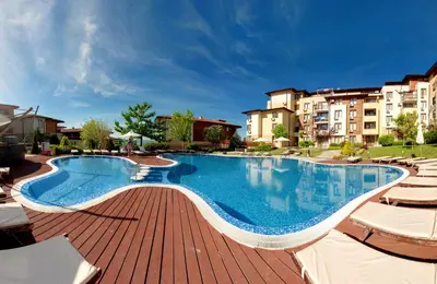 a large swimming pool with chairs and buildings at Garden of Eden Complex in Sveti Vlas