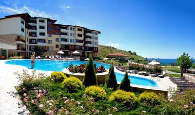 a woman standing in front of a hotel with a swimming pool at Garden of Eden Complex in Sveti Vlas