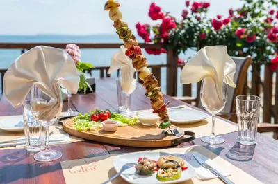 a table with plates of food and wine glasses at Garden of Eden Complex in Sveti Vlas